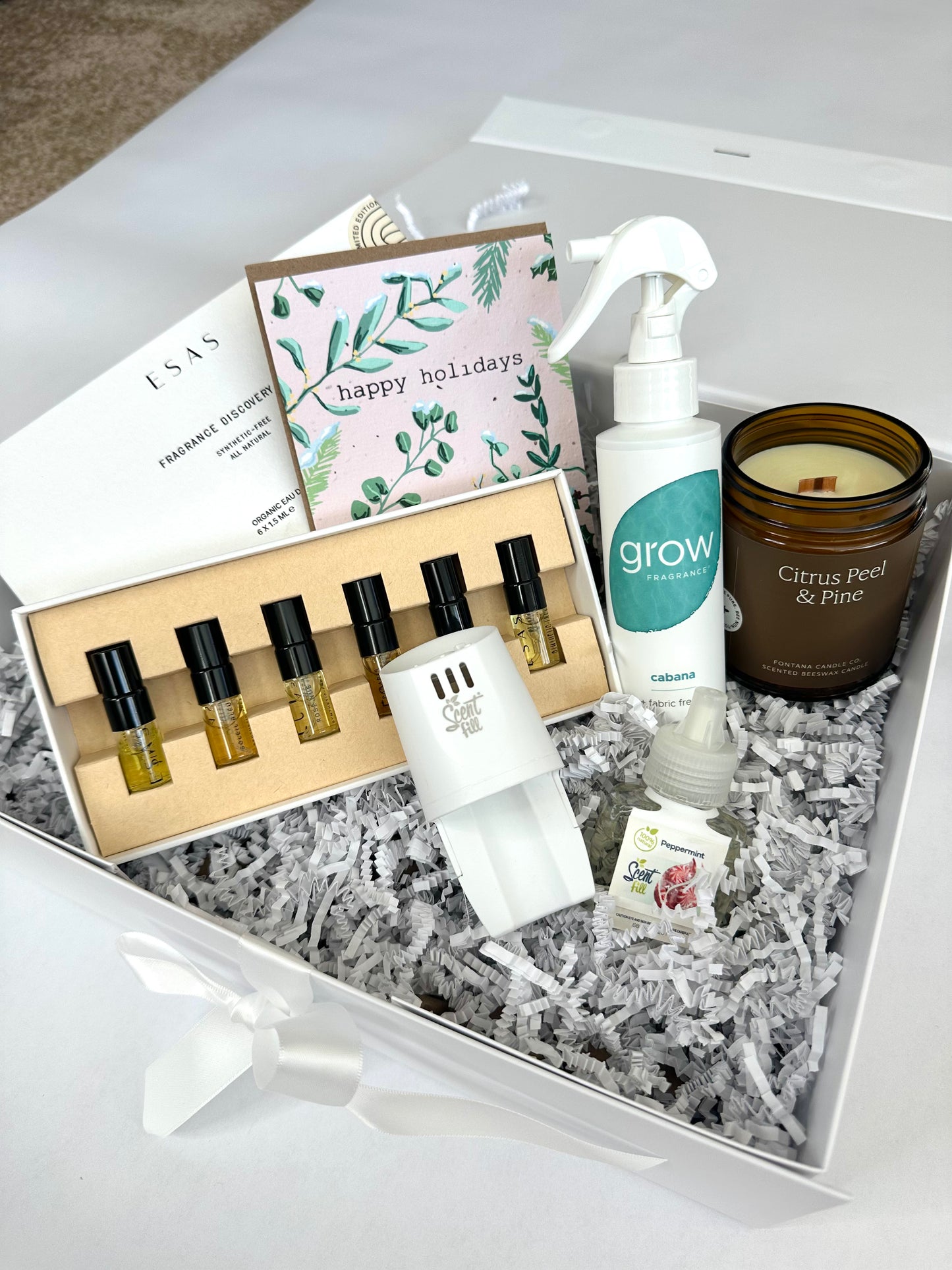 Gift set for fragrance lovers with scented products, candles, and a card on a white surface