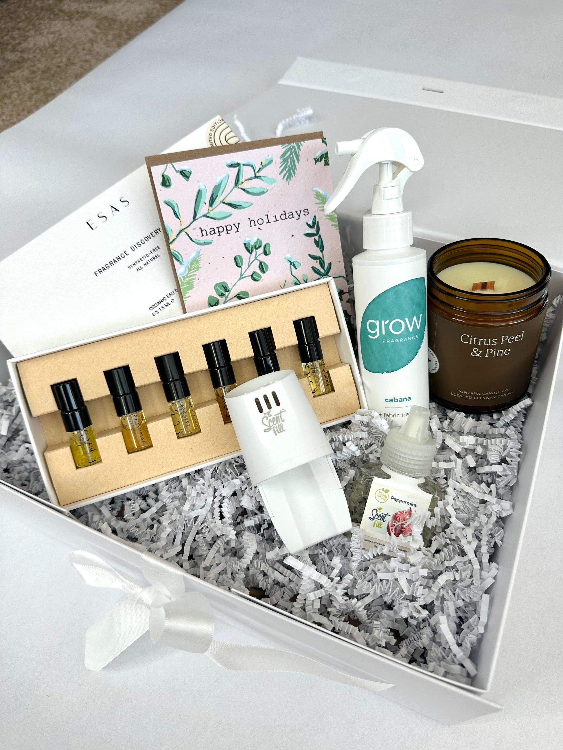 Gift set for fragrance lovers with scented products, candles, and a card on a white surface