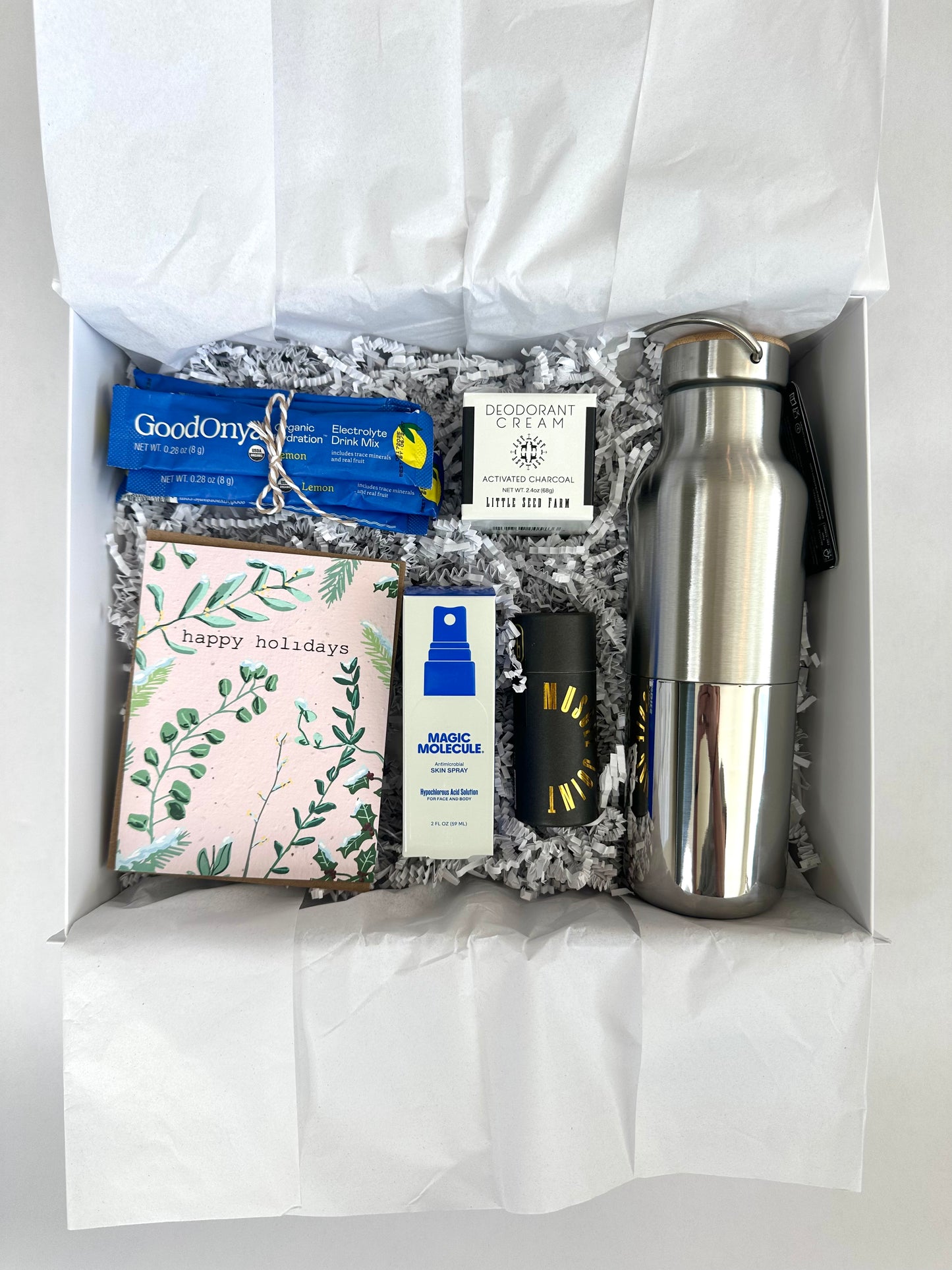 Non-toxic exercise gift box with various items including a silver water bottle, skincare products, and a pouch.