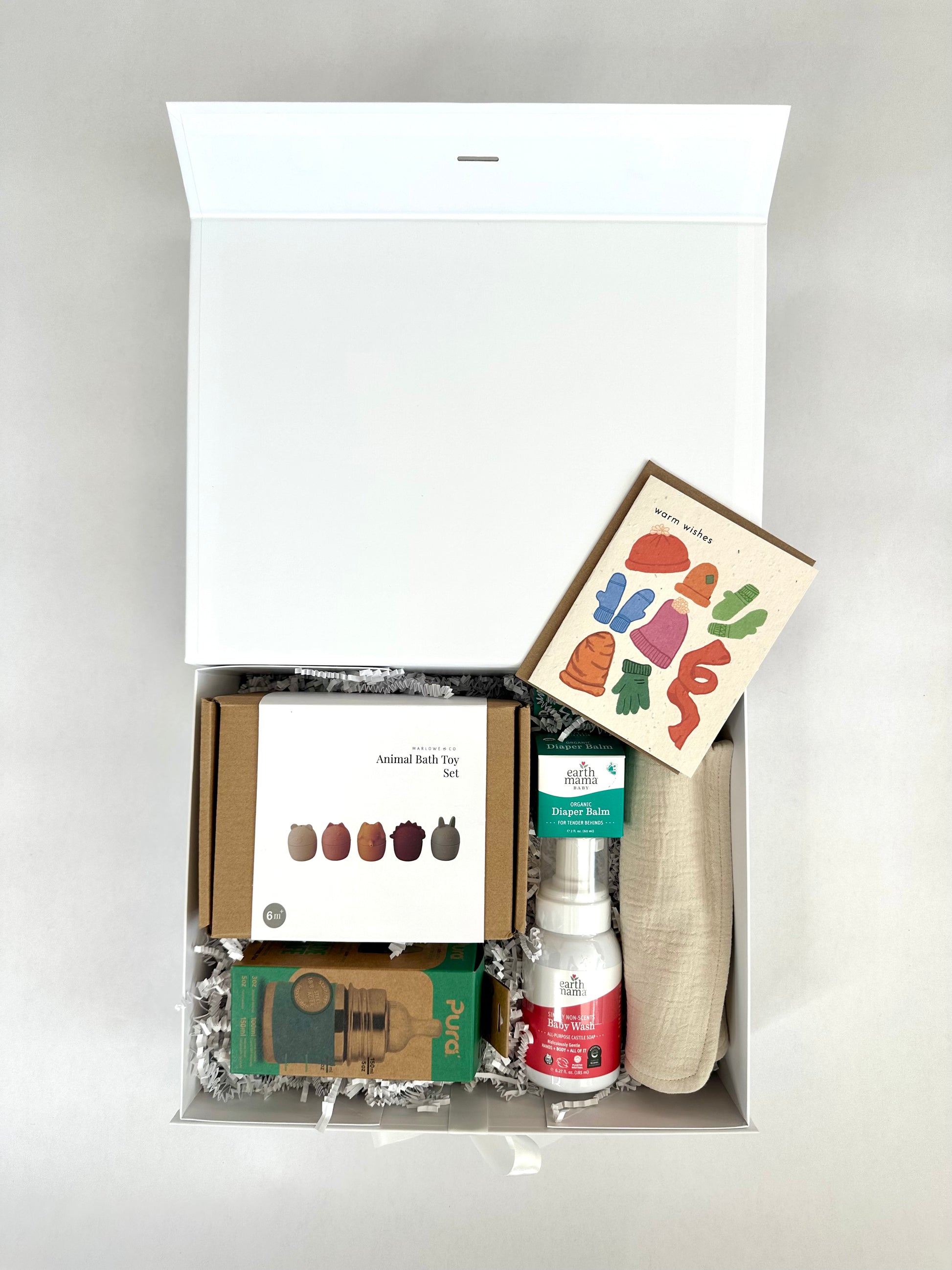 Organic gift box for babies with various items including a book, small bottles, and packaging on a light gray background